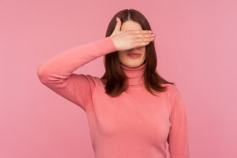 Rózsaszín pulcsis nő eltakarja a szemét