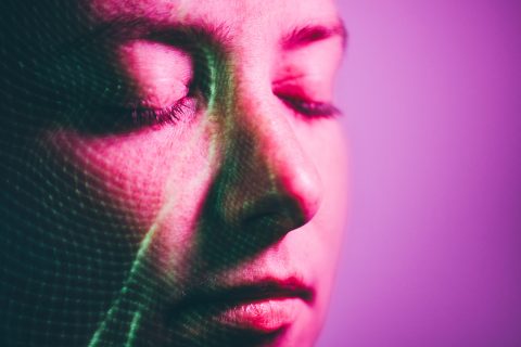 Egy behunyt szemű nő arcára lila fény vetül