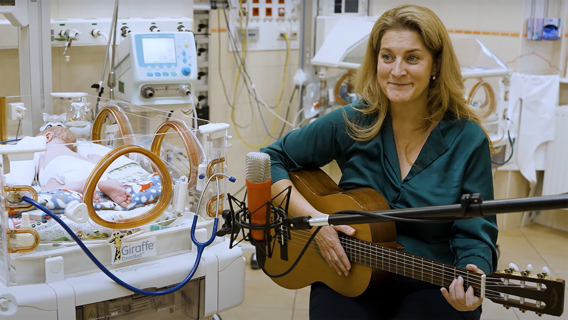 hazay-timea-zenevel-gyogyitja-az-intenziv-osztalyos-babakat | Marie Claire Hazay Tímea gitárral a kezében énekel egy inkubátorban fekvő kisbabának