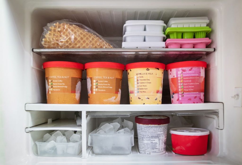 Fagyasztó dobozos jégkrémekkel, jéggel és fagyitölcsérrel