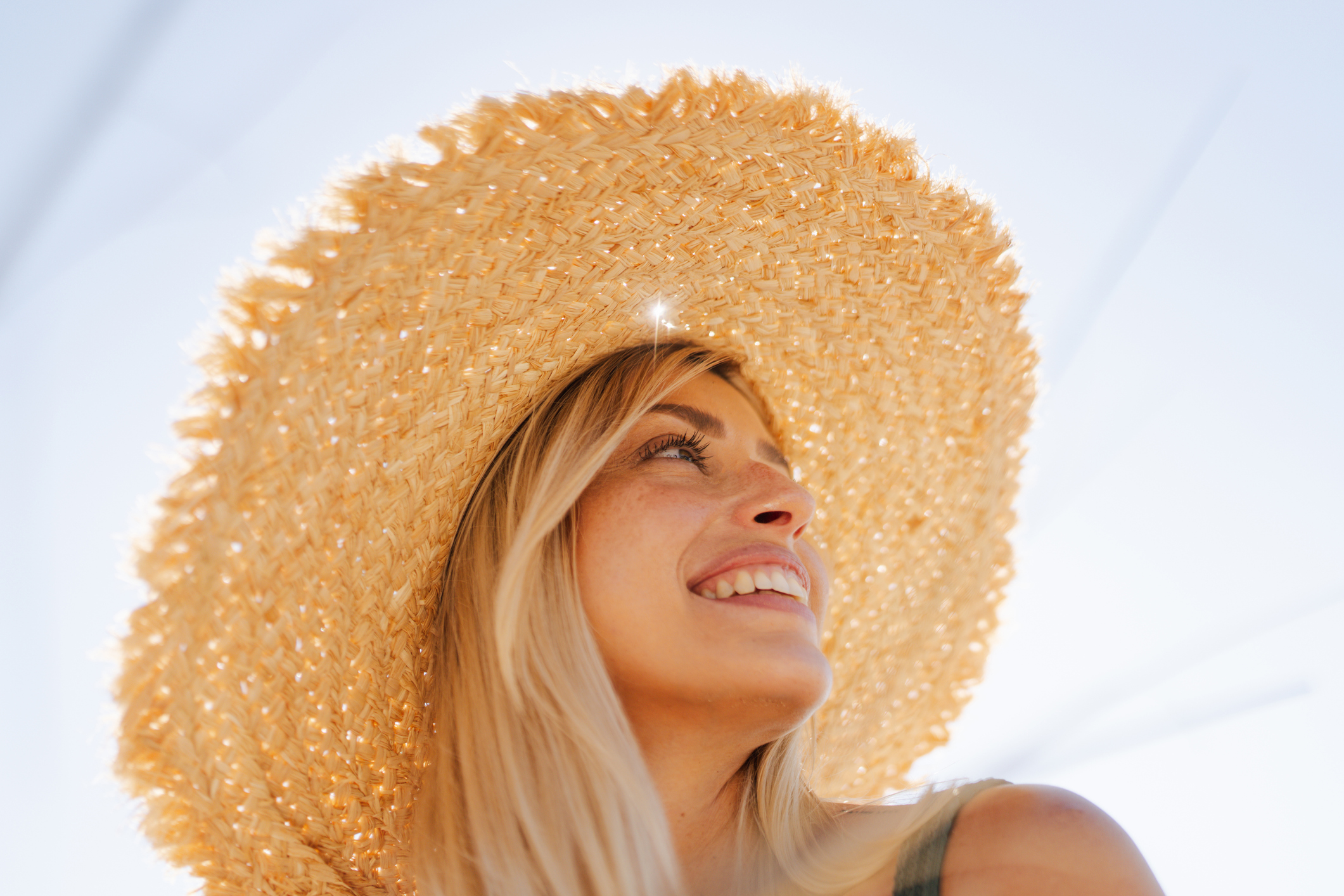 Boldogan mosolygó, fiatal nő szalmakalapban