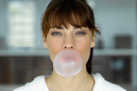 Barna hajú nő rágógumit fúj fel