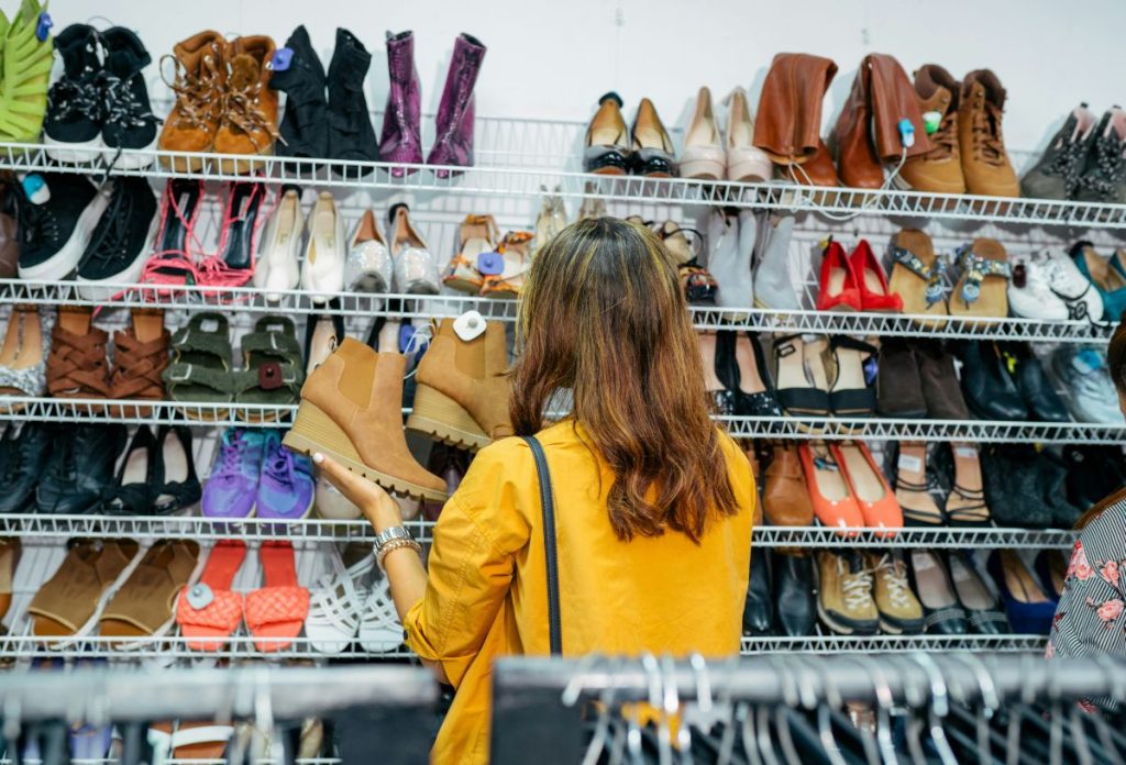 Sárga felsőt viselő barna hajú nő cipőboltban barna bokacsizmát nézeget