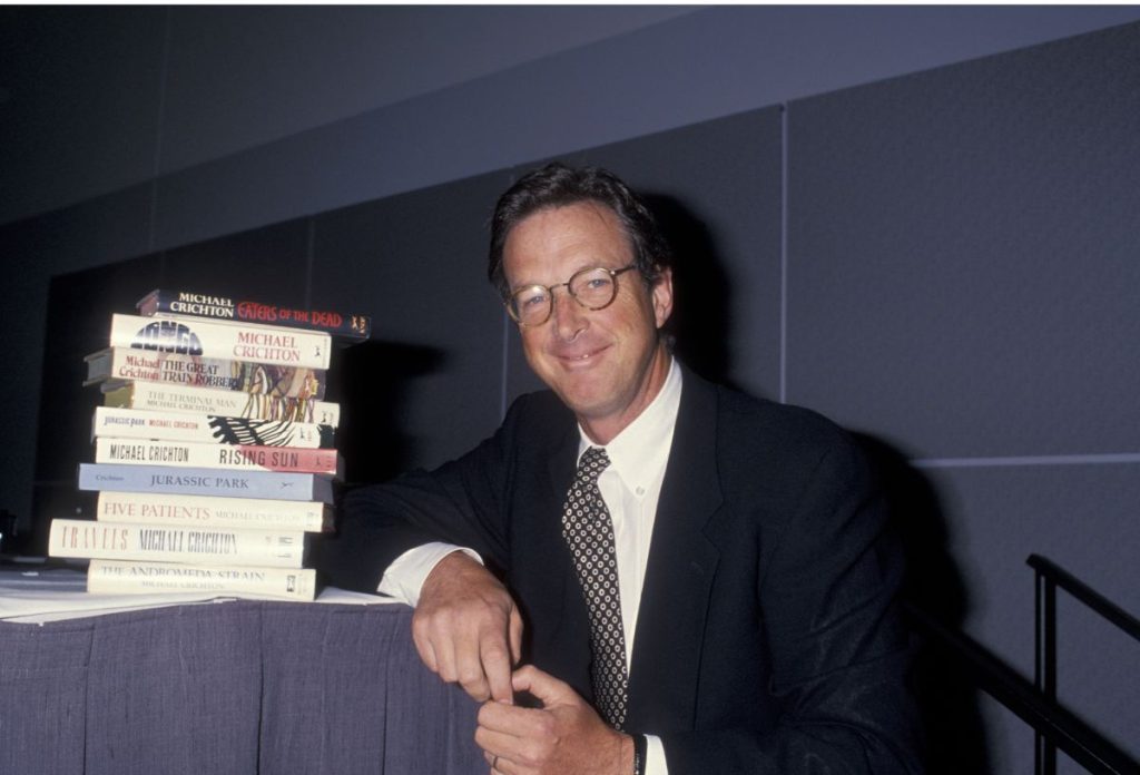 Michael Crichton író a könyvei mellett könyököl