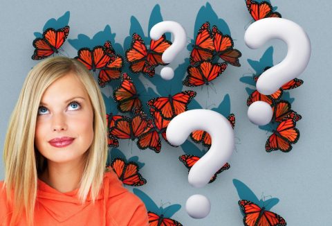 Szőke nő felfelé néz narancs lepkés háttér előtt, fehér kérdőjelek