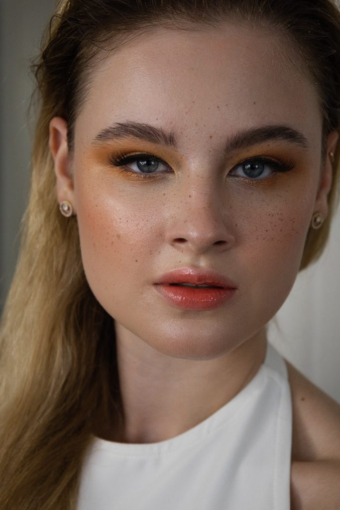 Szeplő smink narancs szemhéjfestékkel és arcpírral hosszú hajú nő arcán