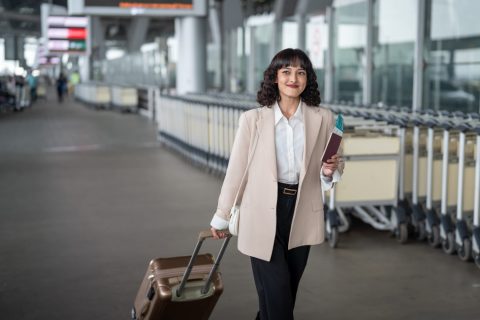 fehér kabátos nő bőrönddel utazni indul