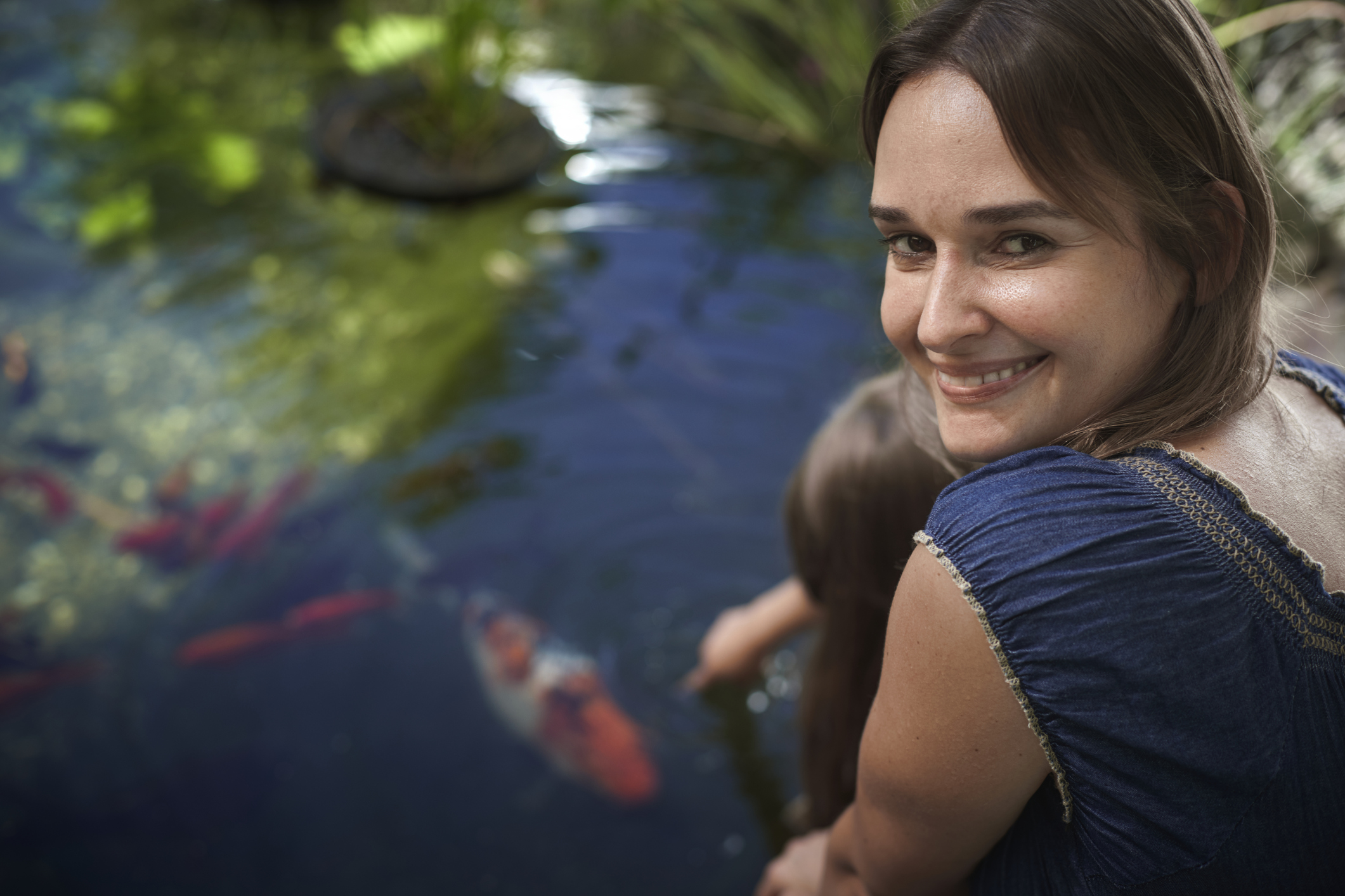 Nő mosolyog a kerti tó mellett
