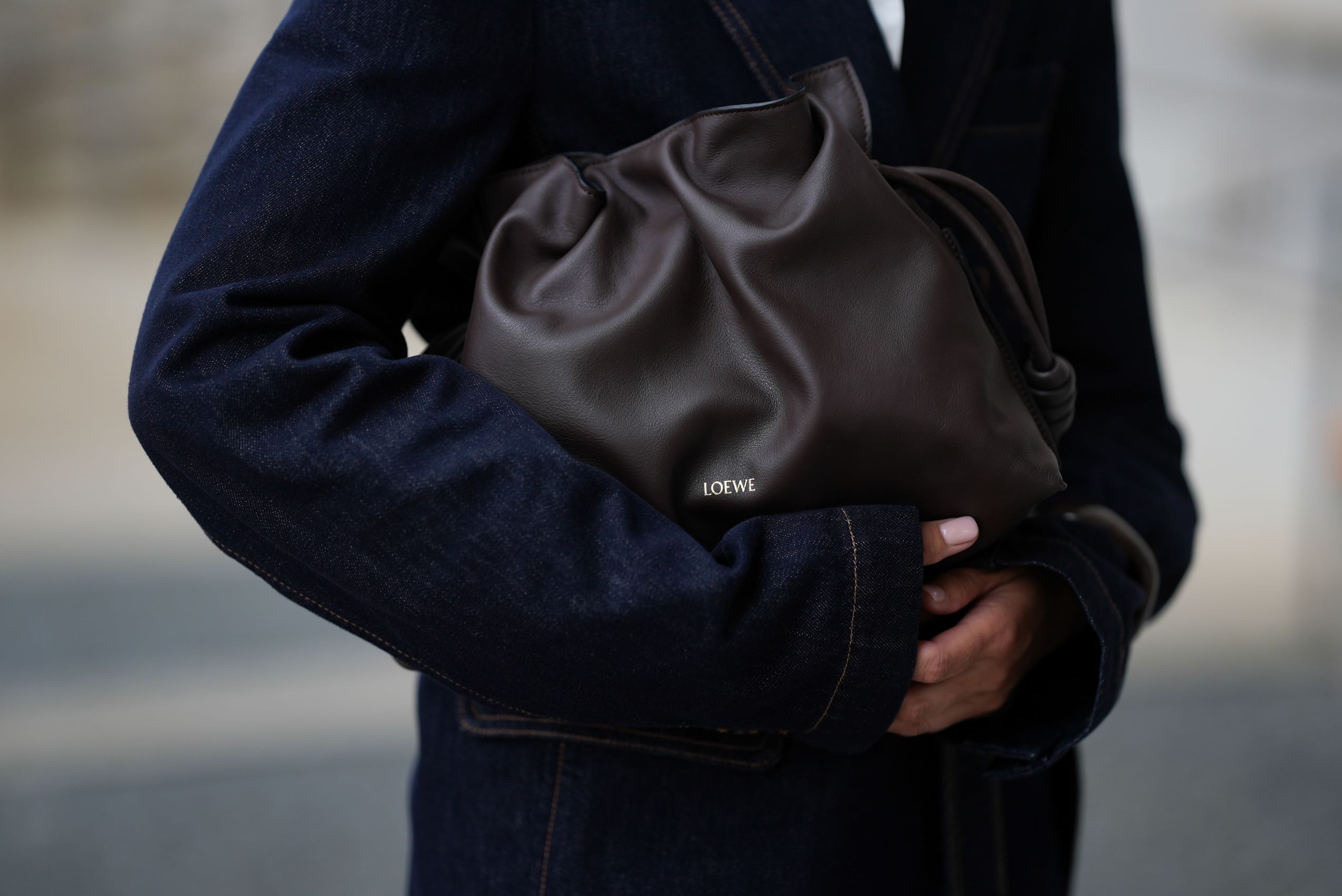 Nő fekete kabátban gyűrt táskát tart