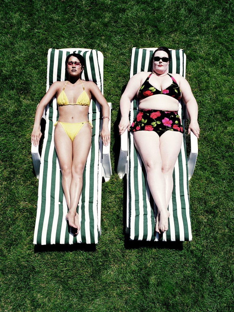 Sovány és túlsúlyos lány fürdőruhában napoznak egymás mellett