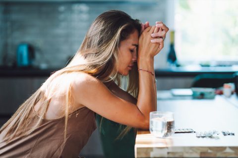 Egy nő, aki magába roskadva támaszkodik az asztalra