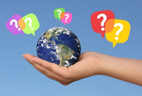 Nő a tenyerében földgolyót tart, színes kérdőjelek körülötte