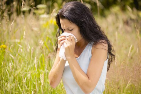 Nő fújja az orrát a szabadban