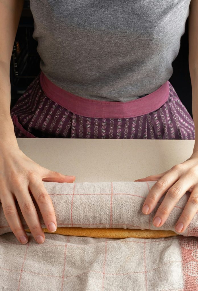 Nő konyharuhába tekeri a frissen sült piskótát