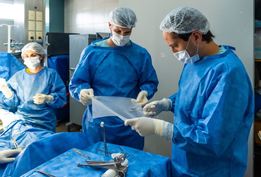 Sérvműtéthez hálót vágnak sebészek a műtőben