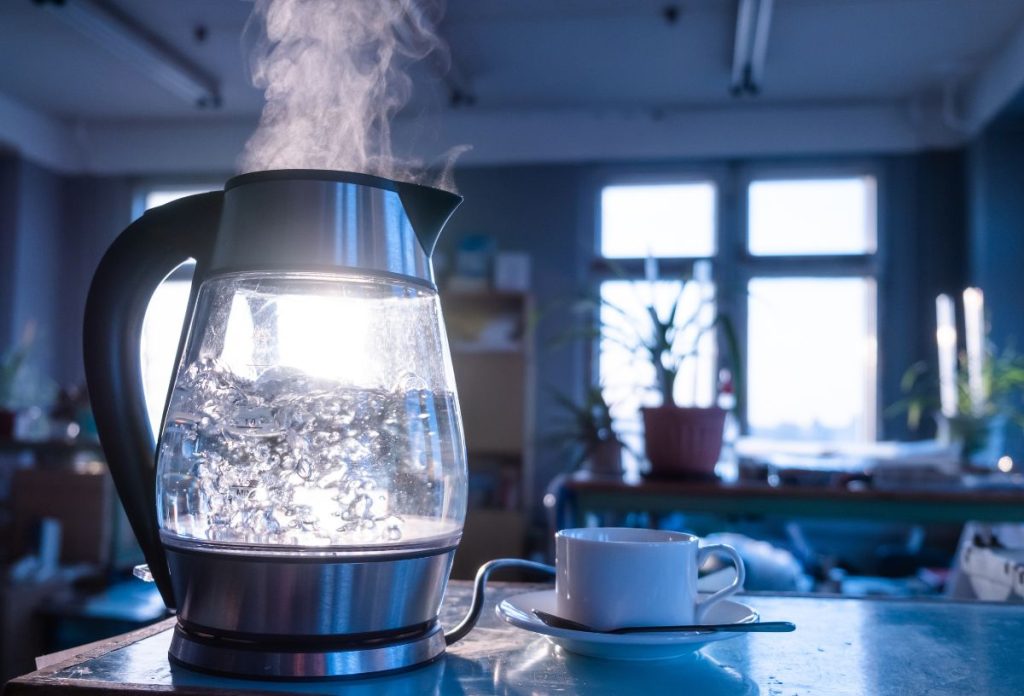 Üveg vízforralóban felforrt víz kékes fényben