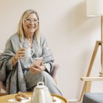 Középkorú nő otthon ülve kávézik