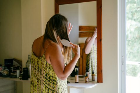 Nő a haját fésüli a tükör előtt