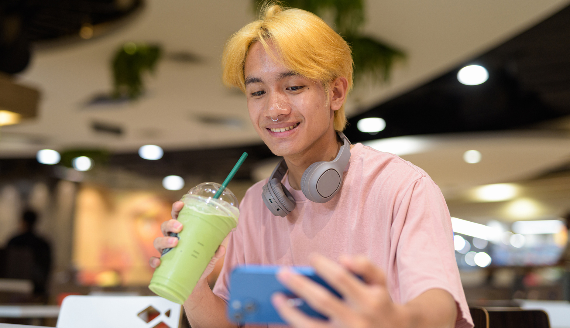 Fiatal ázsiai fiú matcha lattéval a kezében szelfizik