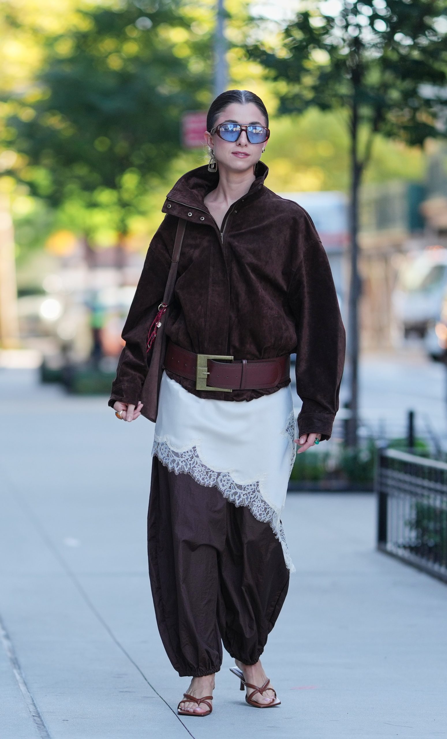 Egy nő oversize, sötétbarna velúr zipzáras dzsekiben és balloon nadrágban