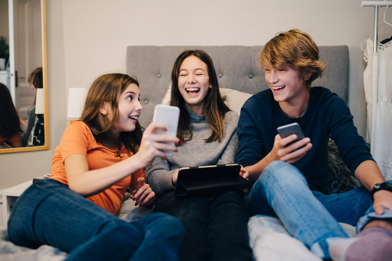 Három tinédzser mobiltelefonnal a kezükben