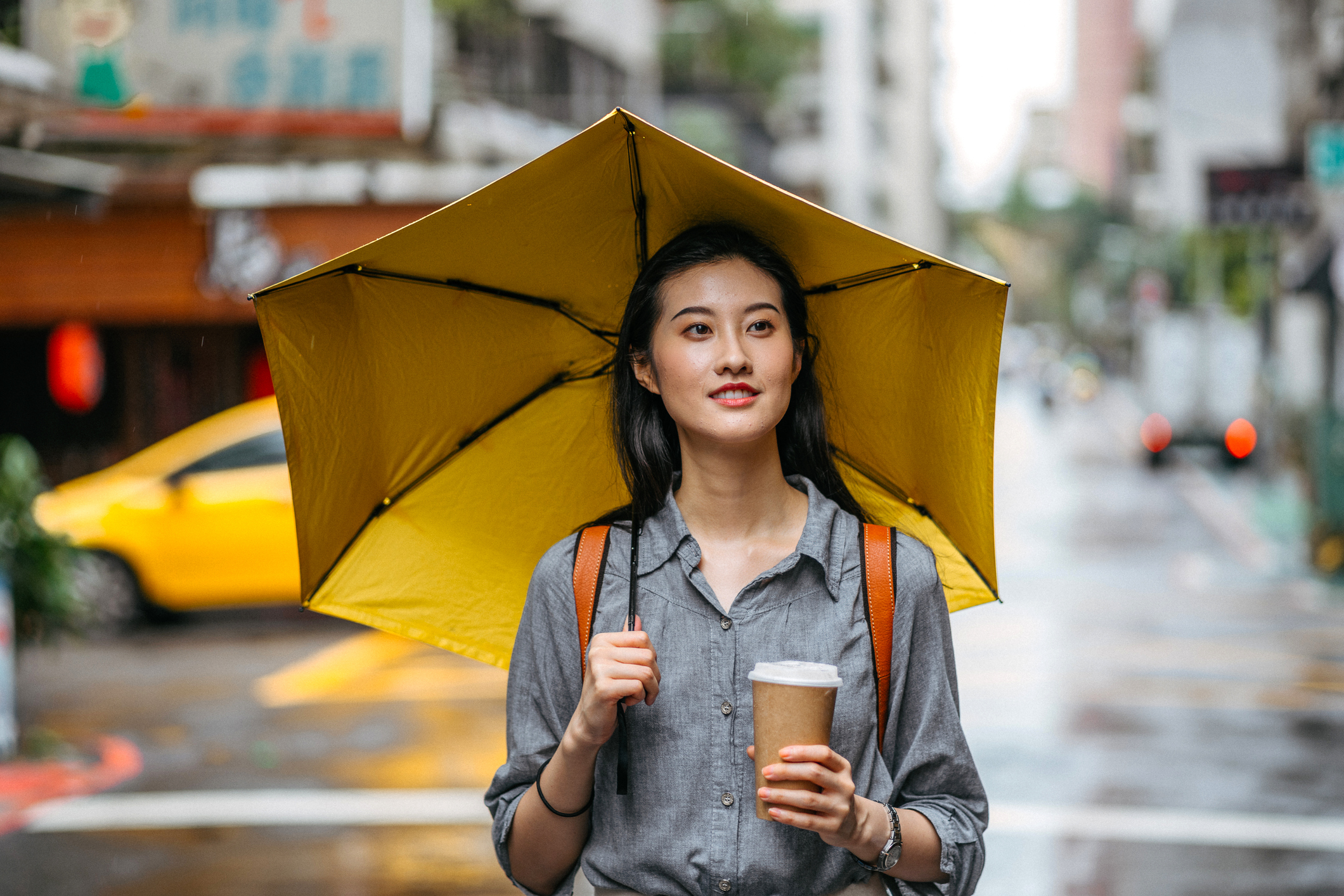 fiatal nő az esőben sétál esernyővel a kezében