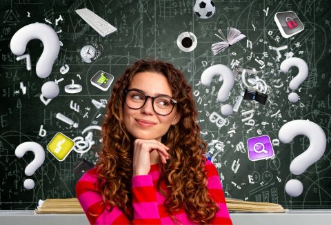 élénk magenta színű pulóverben gondolkodó szemüveges, barna hajú nő, kaotikus tudományos háttér előtt