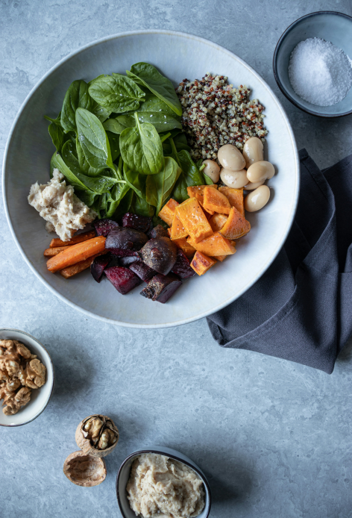 Minimalista tálalással színes ételek fehér mély tányérban: sárgarépa, bébipsenót, fehérbab, cékla, édesburgonya, quinoa