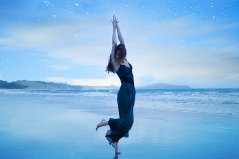 Egy nő táncol a csillagos égbolt alatt