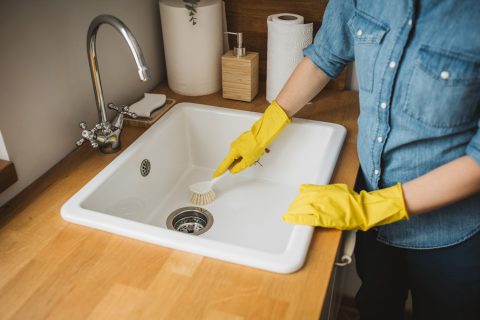 Egy nő kefével takarítja a mosogatót