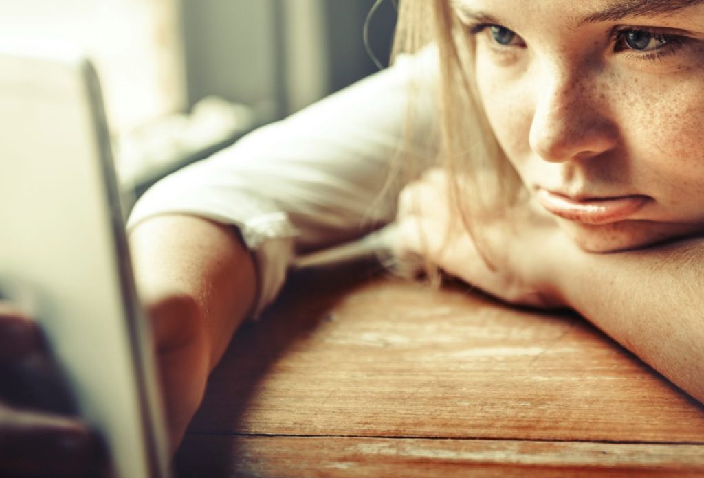 Közeli fotó unatkozó arcú, telefonozó nőről