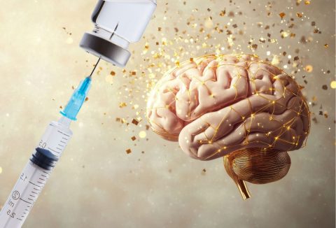 Vakcinát felszívó injekciós tű és emberi agy körül arany csillámok koncepciófotó