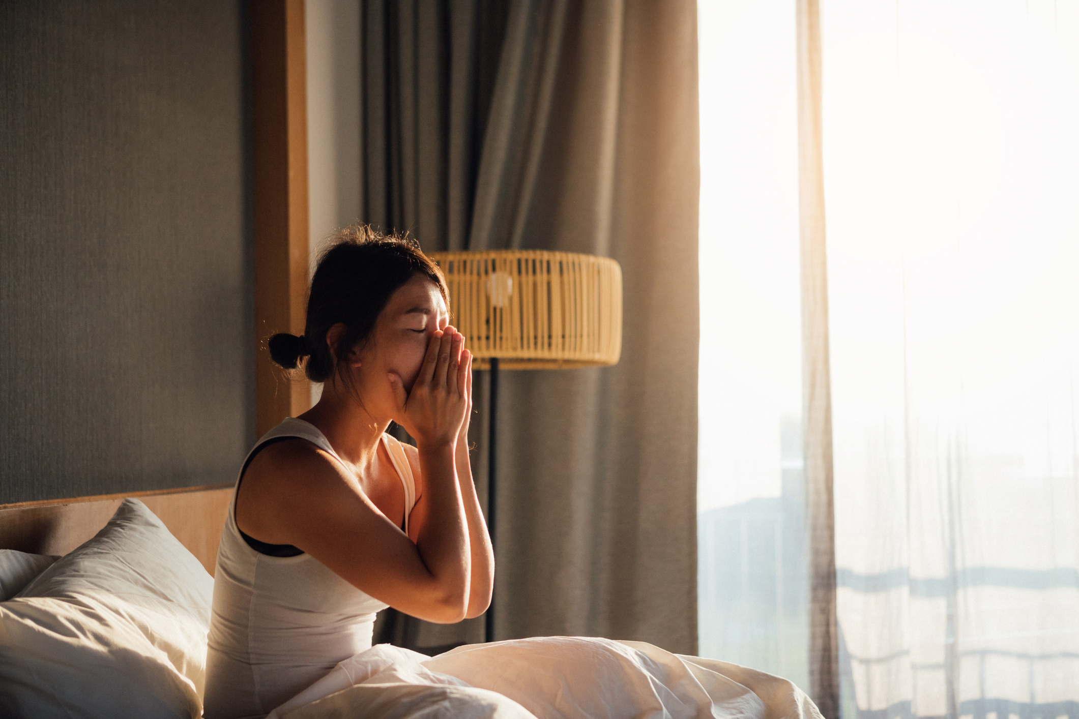 Nő fáradtan ül az ágyban