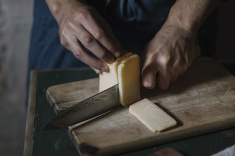 Férfi házi sajtot vág egy vágódeszkán