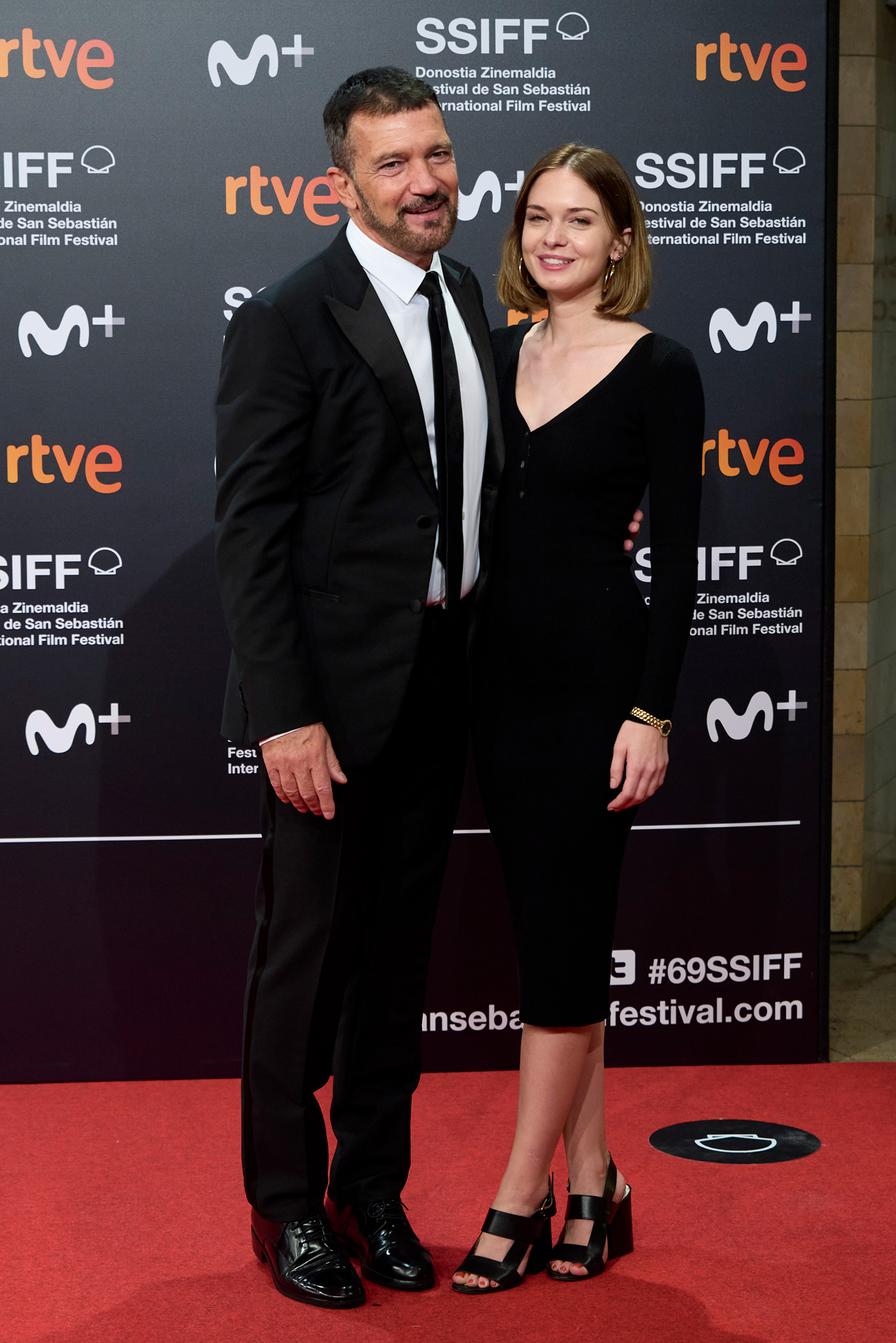 Az öltönyt és nyakkendőt viselő, Antonio Banderas lányával, Stella Banderasszal pózol a vörös szőnyegen, aki hosszú fekete ruhát visel és mindketten mosolyognak