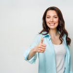 Fiatal nő mosolyog felfelé tartott hüvelykujjal