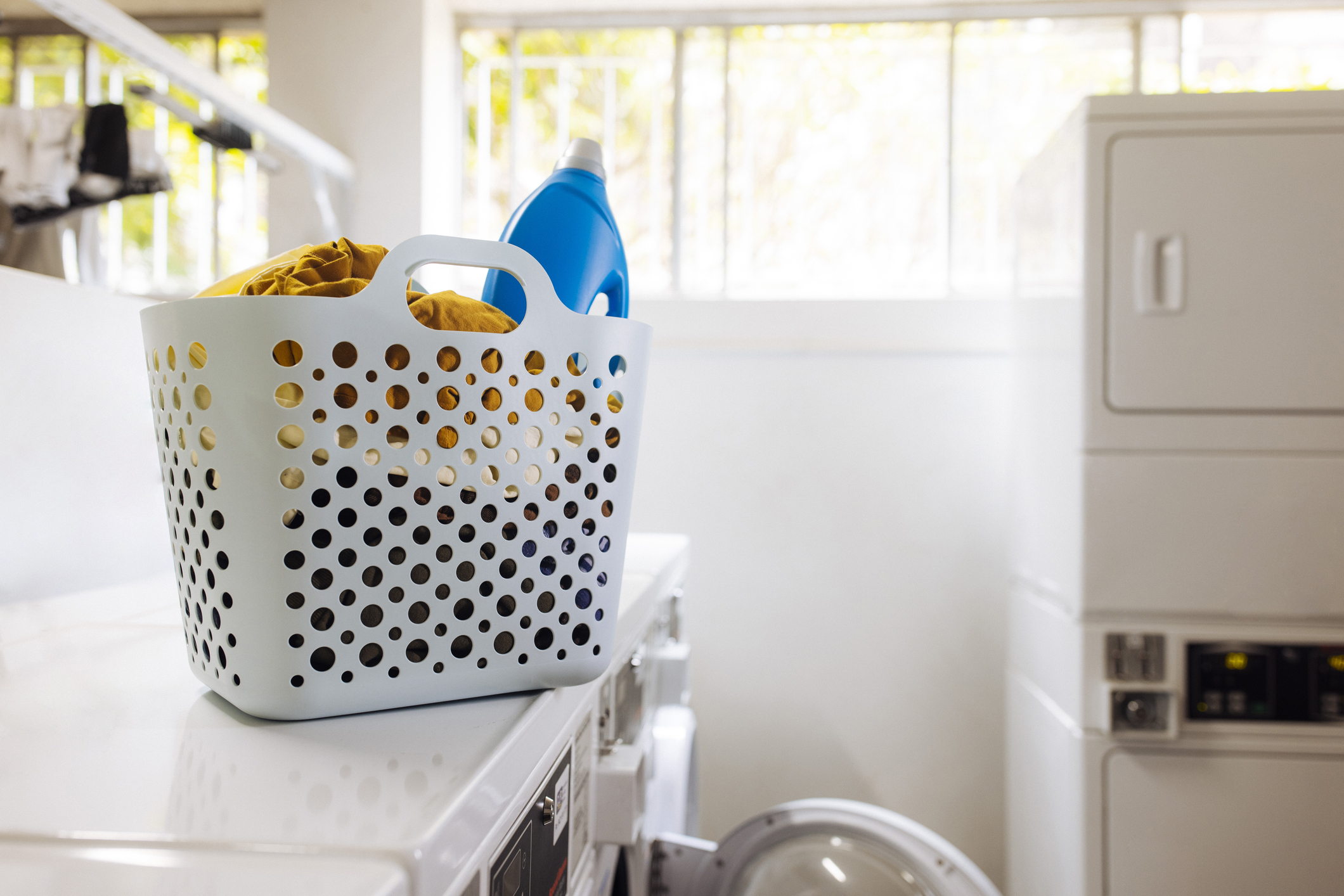 Ruhák és mosószeres táska egy mosógépen az önkiszolgáló mosodában, emberek nélkül.