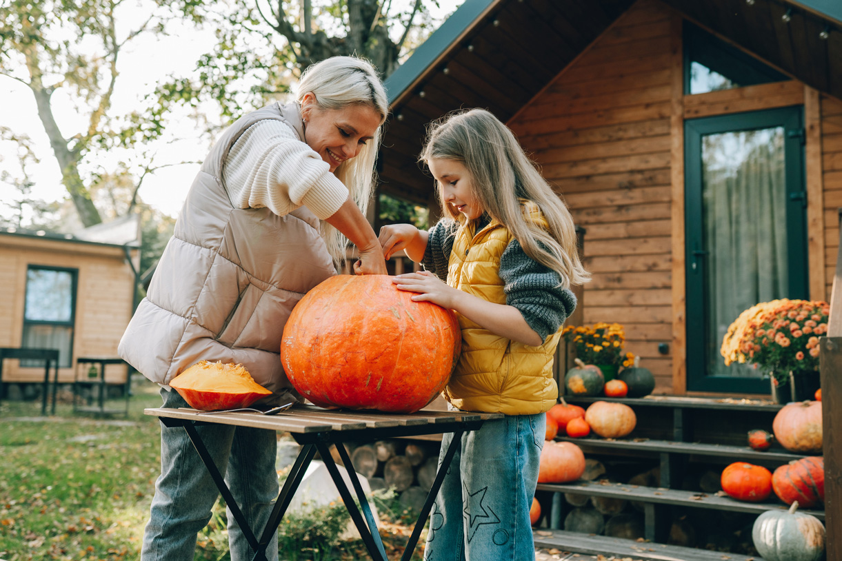 halloween-2025-tokfaragas-5-egyszeru-lepesben | Marie Claire Egy nő és egy kislány halloweeni tököt faragnak a kertben