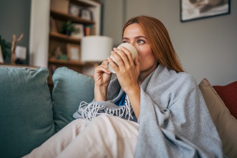 takaróba burkolózó nő a kanapén ül