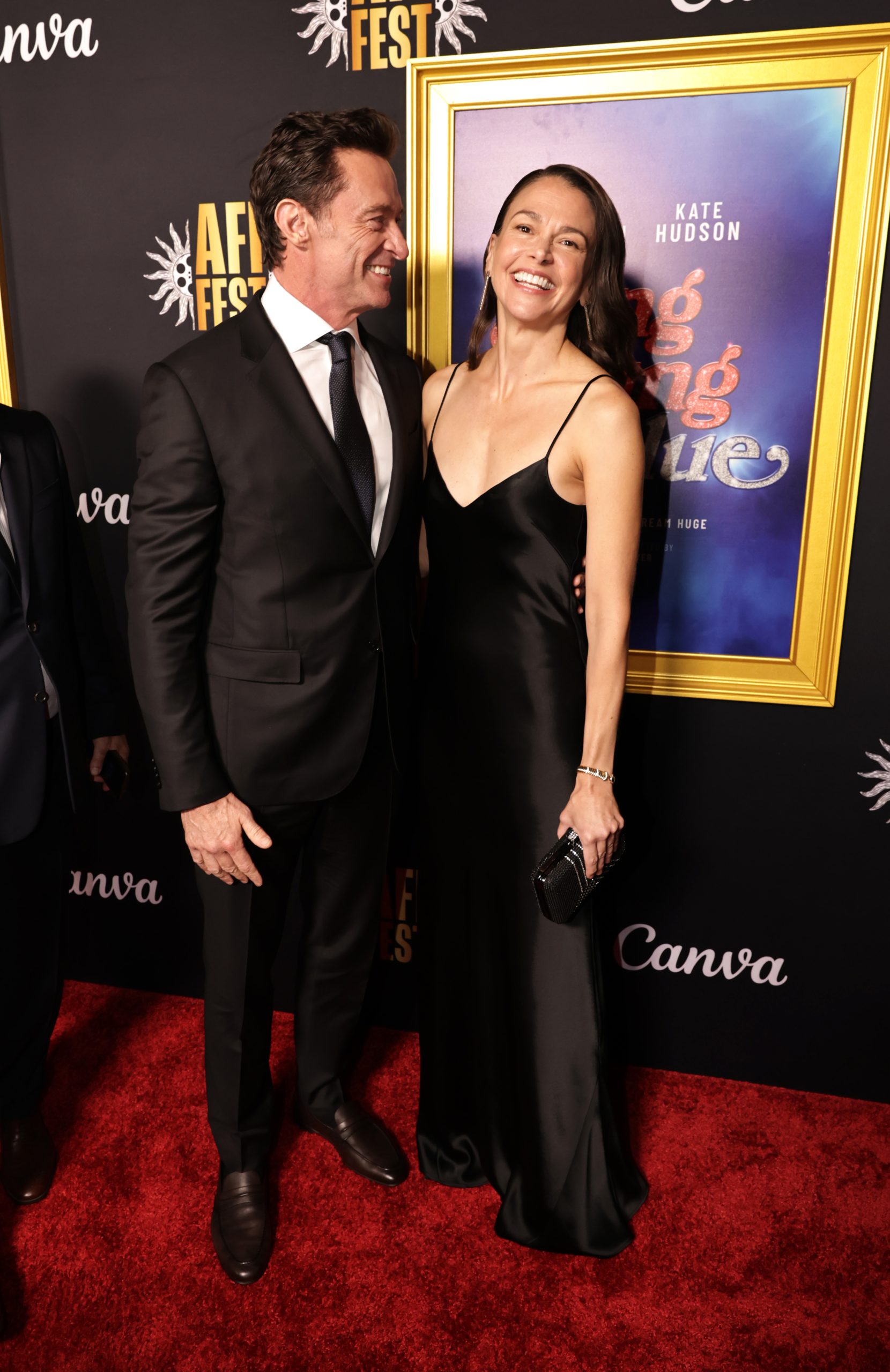 Hugh Jackman fekete öltönyben és Sutton Foster fekete estélyiben nevetnek: párként debütáltak a színész új filmje, a Song Sung Blue premierjén