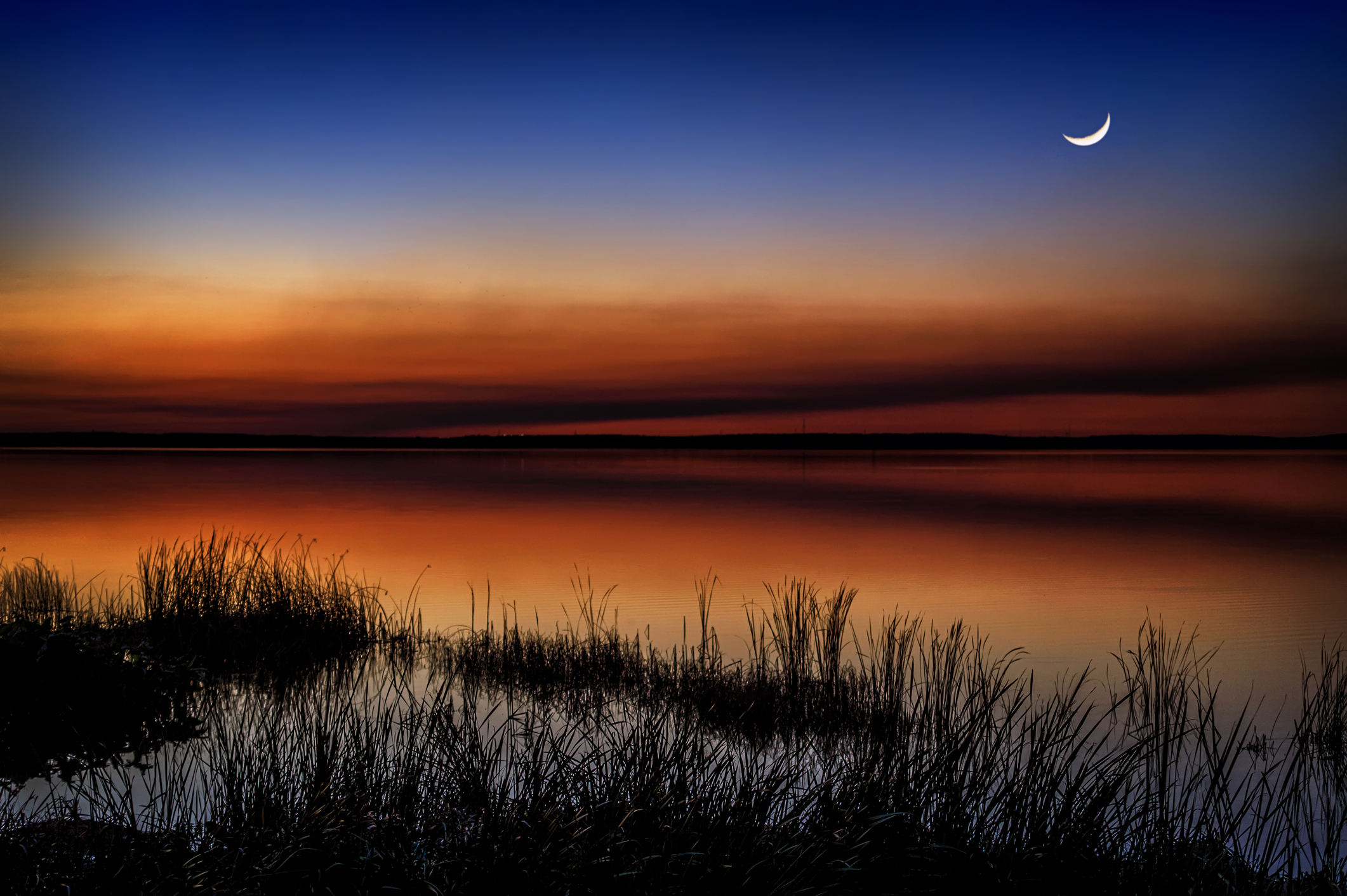 Újhold az égen egy tó fölött