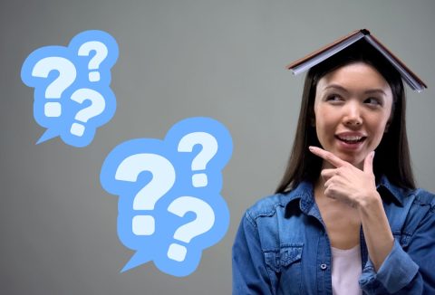 Barna hajú nő könyvvel a fején gondolkodva fogja az állát, kék kérdőjelek