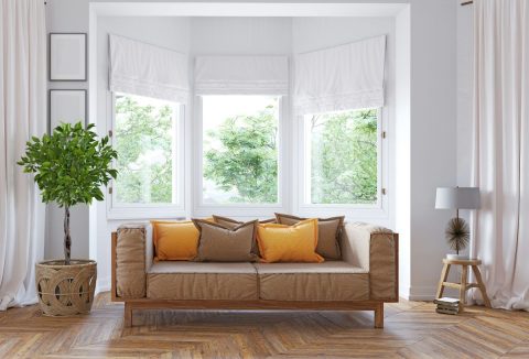 Minimalista, letisztult nappali barna kanapéval, díszpárnákkal, szobanövénnyel és fehér függönyökkel