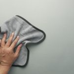 Szürke mikroszálas törlőkendővel konyhaszekrényt törlő kéz