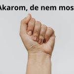 Ökölbe szorított, felfelé mutató női kéz fehér háttér előtt.