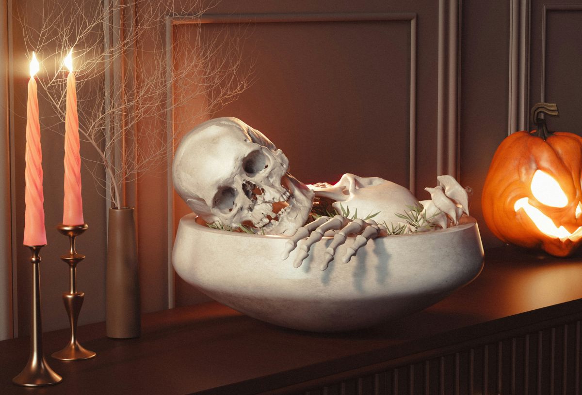 Halloween dekoráció gyertyákkal, világító tökkel és egy tálban csontvázdarabokkal, koponyával