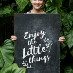 Nő a kezében tart táblát "Élvezd az apró dolgokat" felirattal