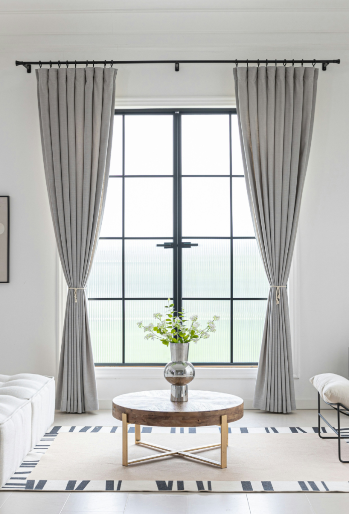 Fehér, minimalista berendezésű szobában szürke, hosszú függöny francia ablak előtt
