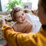 Mosolygós kislány két copfjával játszik az anyukája