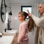 Nagymama kislány frizuráját csinálja